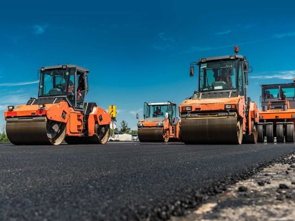 The construction site of pavement and compaction machinery.