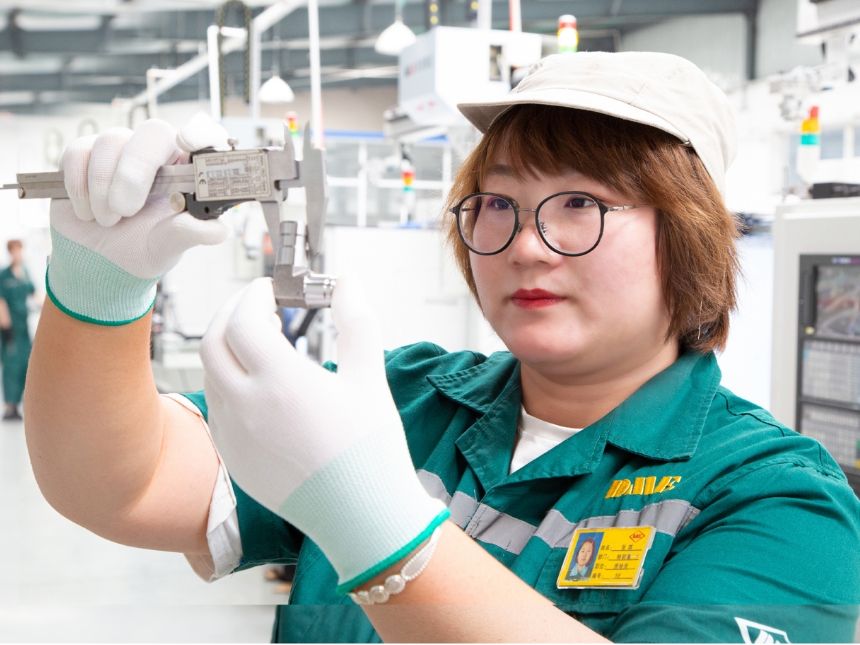  A worker is testing the dimension of adaptor beside of the machine